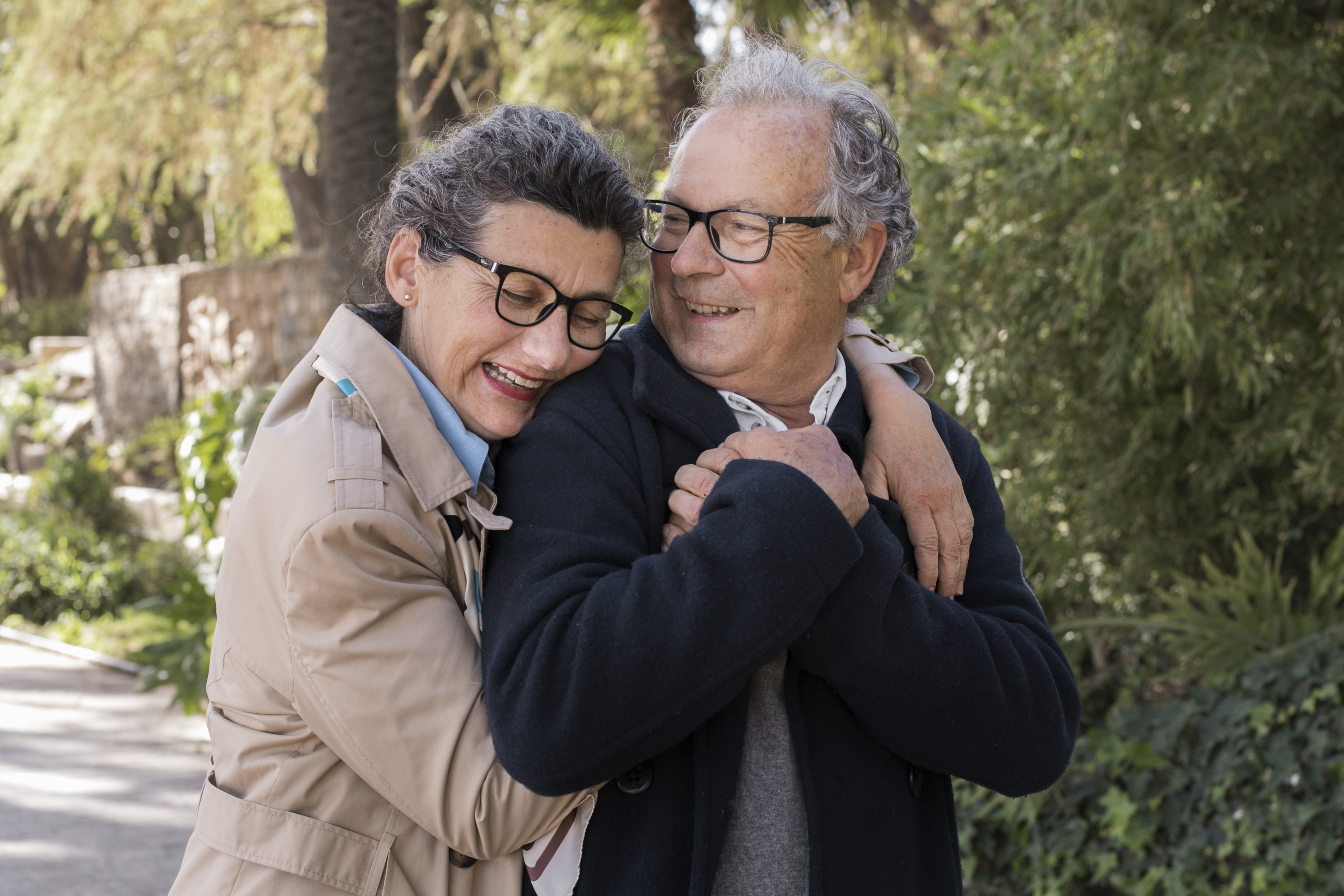 Casal de idosos sorrindo, abraçados ao ar livre